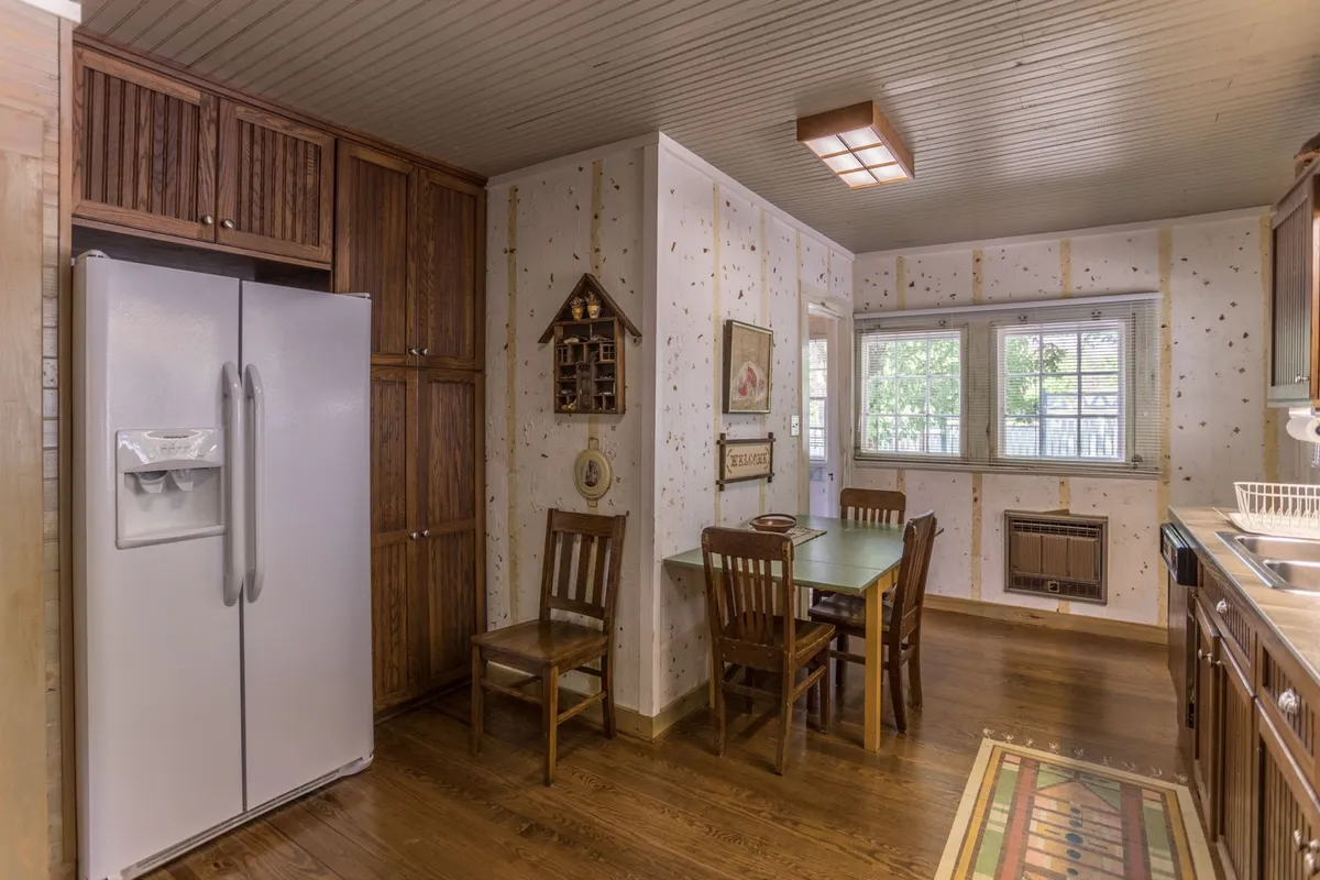 A bright, nostalgic kitchen and dining area featuring a spacious table, large windows letting in natural light, and a fully equipped kitchen—perfect for shared meals, family cooking sessions, and easy conversation.